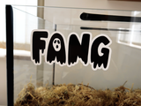 A Furnishables static cling name sticker in a spooky style font, stuck to the front of a glass pet enclosure.