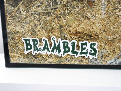 A Furnishables static cling name sticker in a spooky style font, stuck to the front of a glass pet enclosure.